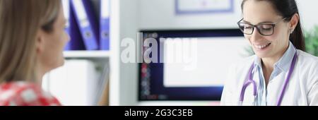 Woman doctor writing in medical history and talking with patient Stock Photo