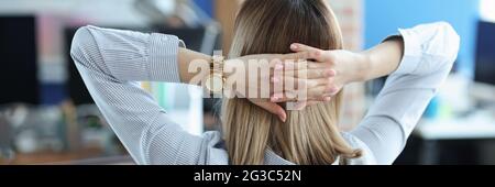 Woman sitting at table and holding her hands behind head Stock Photo