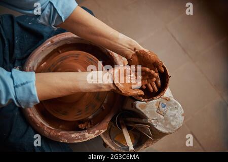 Craft woman working in pottery workshop while making ceramic tableware Stock Photo