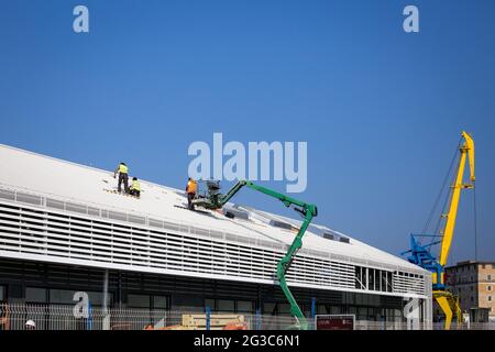 Construction workers with protective clothing work on the roof of the building Stock Photo