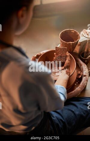 Beautiful young craft woman modeling earthenware bowl in pottery workshop Stock Photo