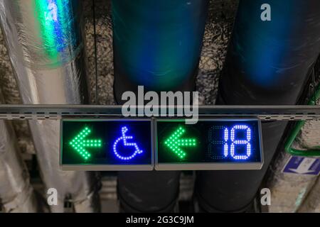 Plumbing under ceiling of underground parking with traffic control signs. Place sign for disabled people. Number of free seats sign. Stock Photo