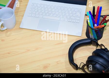 Top view of a workplace with laptop computer pen headphones book and cup with blank space on the desktop and online learning tools, Concept remote stu Stock Photo