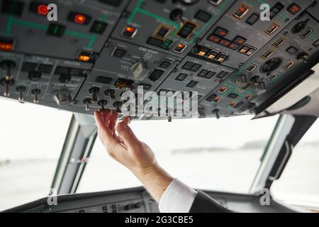 Male pilot turning button on passenger airplane Stock Photo