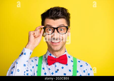 Photo of young excited man happy positive smile amazed surprised hand touch glasses isolated over yellow color background Stock Photo
