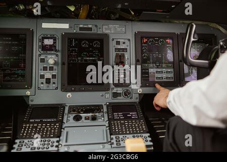 Male pilot pushing button on passenger airplane Stock Photo