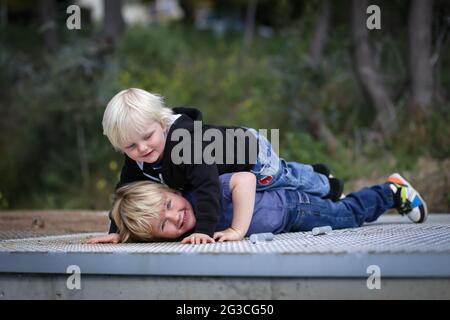 Cute Australian blonde boys lying on each other on the roof - the concept of brotherhood Stock Photo