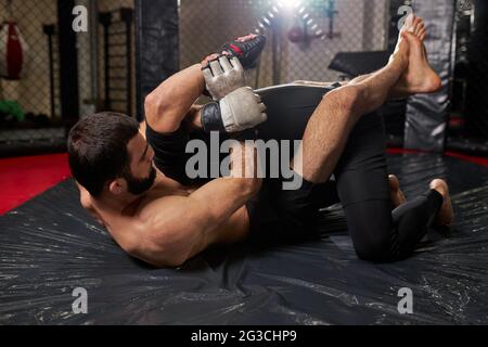 Sports concept of fighting without rules. Two athlete wrestlers at gym, training together. fights without boxing rules MMA. sporting battles side view Stock Photo