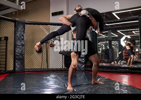 Fighters of MMA boxers are fighting without rules in cage ring at gym. MMA fighters in ring preparing for championship. boxing fights without rules Stock Photo