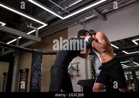 young MMA boxers fighters fight in fights without rules in ring octagons. Mixed martial artists during fight. sport and boxing concept Stock Photo