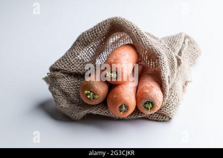 Carrots  in a burlap bag on white wooden table Stock Photo