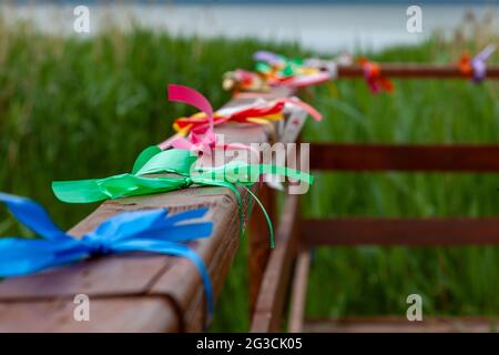 Multi-colored ribbons tied to the wooden railing of the bridge. Stock Photo