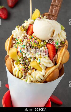 Hong kong or bubble waffle with ice cream, fruits, chocolate sauce and colorful candy Stock Photo