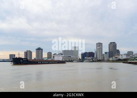 NEW ORLEANS, LOUISIANA - DECEMBER 5, 2020: Cargo ship headed downriver with city skyline in background Stock Photo