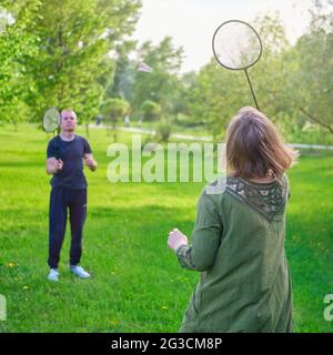 Family playing badminton in the park, mom and son with rackets and shuttlecock Stock Photo