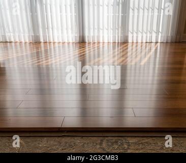 Vertical blinds cast shadows on a newly installed Brazilian Cherry hardwood floor Stock Photo