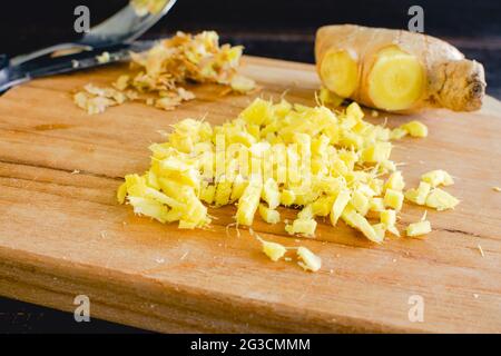 Peeled and Finely Chopped Ginger Root: Diced ginger on a wooden cutting board Stock Photo