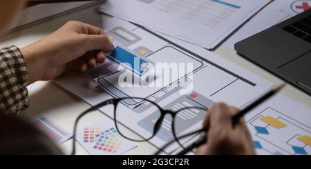 A close-up of an ux ui developer and an ui designer working on a mockup icon interface for a mobile app. Stock Photo