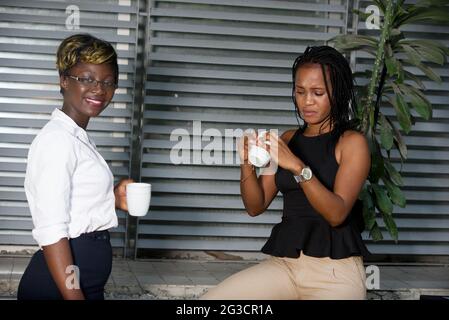 two businesswomen drinking coffee outdoors. Work Balance Concept Stock Photo
