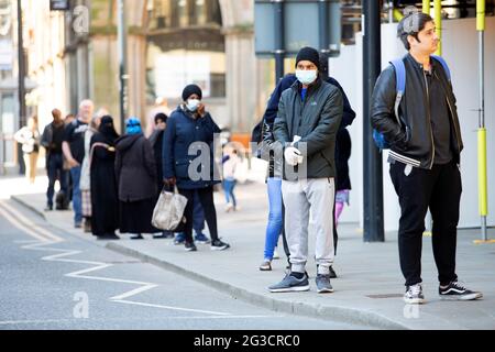 A young man wearing a protective face mask waits outside Barclays bank in Bradford City Centre in west Yorkshire as the coronavirus pandemic continues Stock Photo