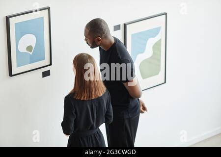High angle portrait of elegant couple looking at paintings in modern art gallery, copy space Stock Photo