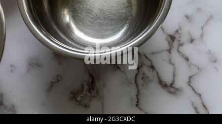 half view of an empty metal round mixing bowl on a marble surface with natural light Stock Photo