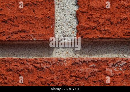 A macro shot of bright red bricks and white mortar in the afternoon sun, focusing on the bumpy texture that the bricks have. Stock Photo