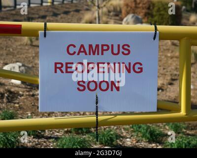 Sign on gate stating school campus will be reopening soon COVID-19 Stock Photo