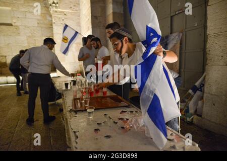 Jerusalem, Israel. 15th Jun 2021 . Israeli ultranationalists March of the Flags. A young boy with a flag grabs a drink after dancing at the entrance to Jerusalem Old City, celebrating the anniversary of Israel's 1967 occupation of Jerusalem's eastern sector. Stock Photo