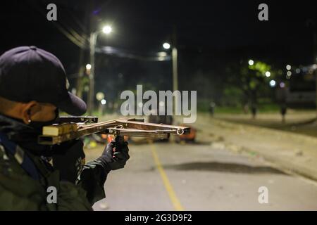 A demonstrator aims a handcrafted crossbow to police as demonstrators and Colombia's riot police (ESMAD) clash during the night of June 14, 2021, in Yumbo - Cali, Valle del Cauca - Colombia as Anti-government protests unveil into their 7th week against the government of president Ivan Duque, unrest and violence that had caused at least 70 dead.