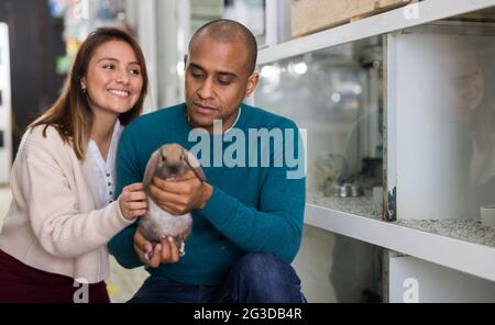 Family couple holding rabbit together in pet shop Stock Photo