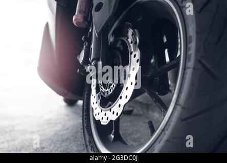 Closeup disc brake of a scooter. Aluminum alloy wheel of motorcycle. Steel rims. Mag wheels of motorbike. Performance wheel and tire of motorcycle. Stock Photo