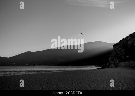 Grayscale shot of waves hitting a sandy seashore of Parque Natural da Arrabida Stock Photo