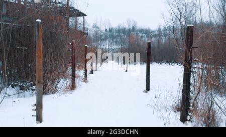 Closeup view of Electric fence poles in the Liban Kamieniolom. The place, where the movie the Schindler´s list was shot. Krakow, Poland. Grove of trees in the background. Whole area covered with snow. Stock Photo