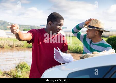 Disgruntled african american farmer reprimanding hispanic contractor Stock Photo