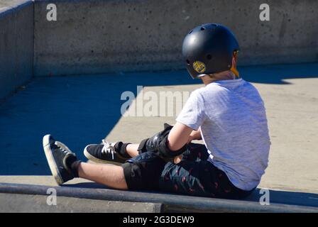 Young Boy with a black helmet resting at a skate park. Stock Photo