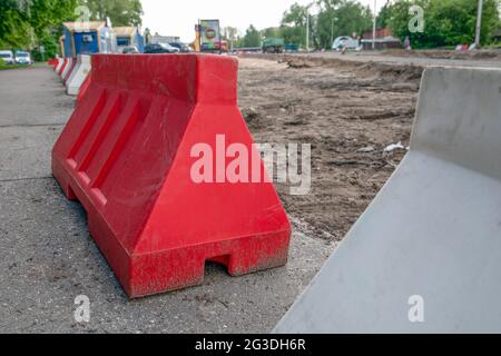 Plastic barriers on the construction site. Water and sewerage reconstruction and road construction in the city. Stock Photo