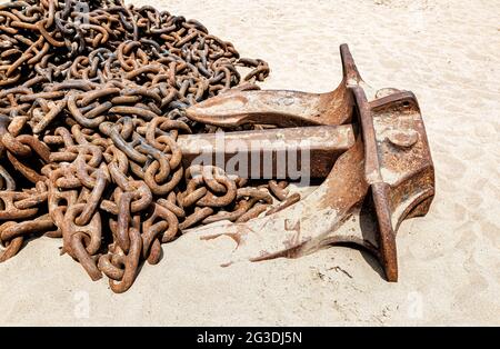 Huge rusty anchor chains with ship anchor of an old ship on the sand beach Stock Photo