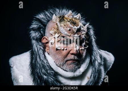 Mysterious warrior enchanted to have thorns on his face, magic and fairy tale concept. Severe sorcerer with beard wearing white fur hood isolated on Stock Photo