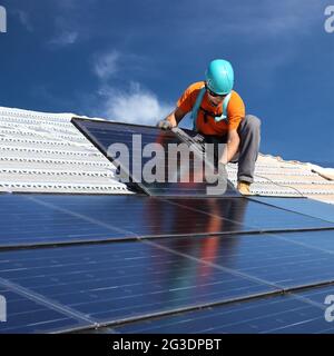 installing alternative energy photovoltaic solar panels on roof Stock Photo