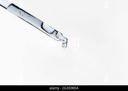 Liquid serum and dropper on a white background top view. Serum drops from a pipette. Stock Photo