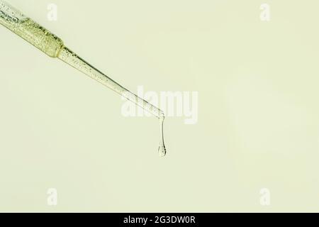 Liquid serum and dropper on a beige background top view. Serum drops from a pipette. Stock Photo