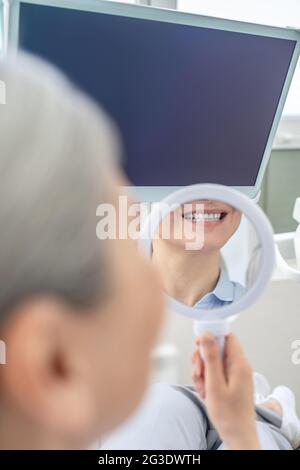 Woman sitting at the dentists office with a mirror in hands Stock Photo