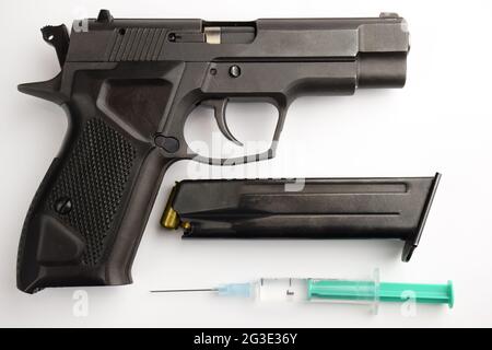 The black gun lies with a clip and a plastic syringe with a needle on a white background Stock Photo