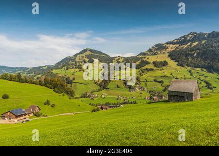 Green meadows and pastures, scattered settlements and alpine huts in the Swiss Alps in Toggenburg in Canton St. Gallen, Switzerland Stock Photo