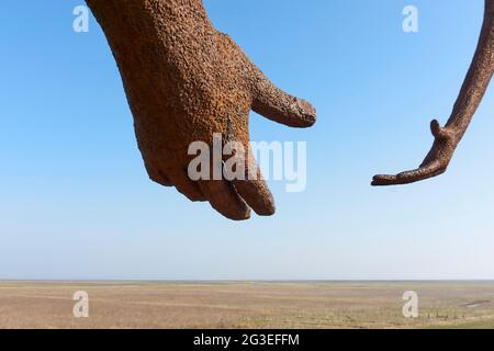 Hands of the waiting for high tide statue of Jan Ketelaar on the seawall near Holwerd. The two metal, five meters high women look out over the sea. Stock Photo