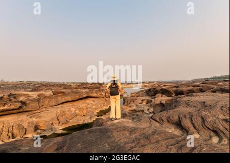 Explorer asian woman standing on rock cliff with looking at paper map in Sam Phan Bok grand canyon of Thailand Stock Photo