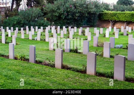 Many white tombstones resting in modern cemetery with lush green grass and green trees. Silence at graveyard with tombstones and flowerbeds. Care of b Stock Photo
