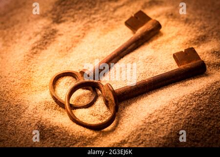 Two old rusty keys in sand in warm tones Stock Photo
