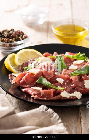 Marbled beef carpaccio on black plate and rustic wooden table Stock Photo